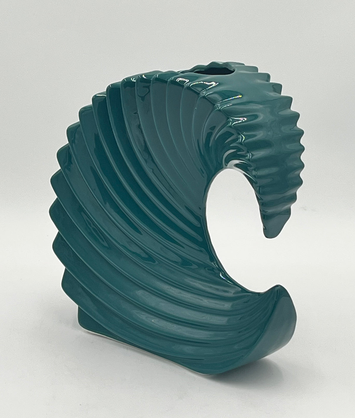 The Cerulean Crest 9x3 Op by Floral supplies Point is a glossy teal ceramic vase with a modern spiral wave design—an ideal sculptural centerpiece for contemporary interiors, shown against a plain white background.